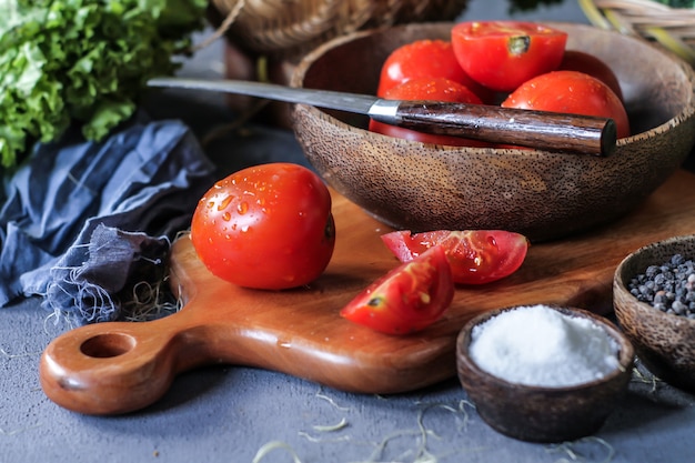 frische Tomaten in einer Schüssel, um Gemüse, Karotten, schwarzen Pfeffer, Mais, Brokkoli. Tomaten in Scheiben schneiden. Tomaten ernten.