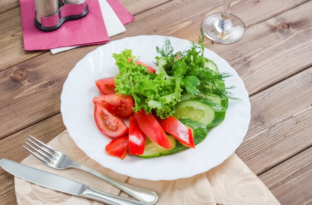 Frische Tomaten mit Gurken, Salat und Dill auf einem weißen Teller