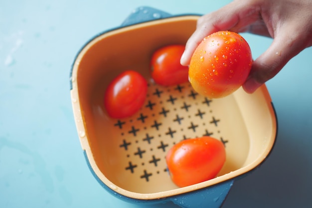 Frische Tomaten mit Wasser in einer Plastikschüssel reinigen