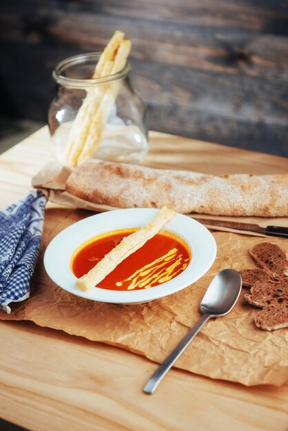 Frische Tomatensuppe in einer weißen Maske mit Brotstangenbrot