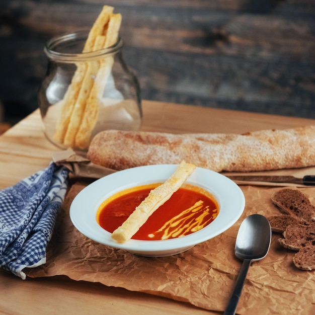 Frische Tomatensuppe in einer weißen Maske mit Brotstangenbrot