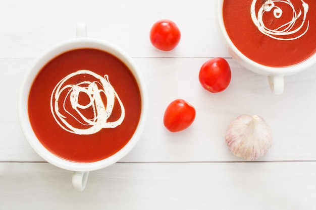 Frische Tomatensuppe in einer weißen Schüssel auf weißem Draufsicht-Kopienraum des Holztischs