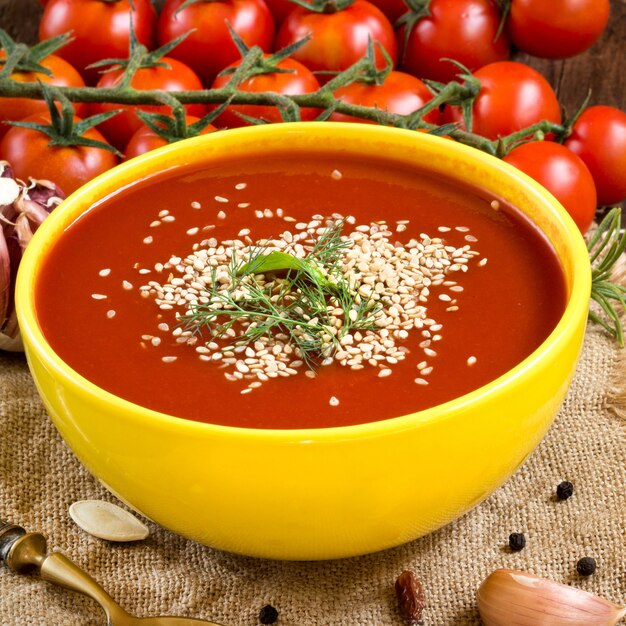 Frische Tomatensuppe mit Gemüse und Löffel auf einem Holztisch