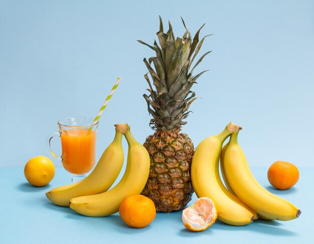 Frische tropische Früchte und ein Glas Saft auf blauem Hintergrund