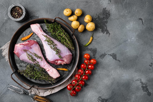 Frische Truthahnkeulen mit Zutaten zum Kochen auf grauem Steintisch Hintergrund Draufsicht flach liegend mit Kopierraum für Text