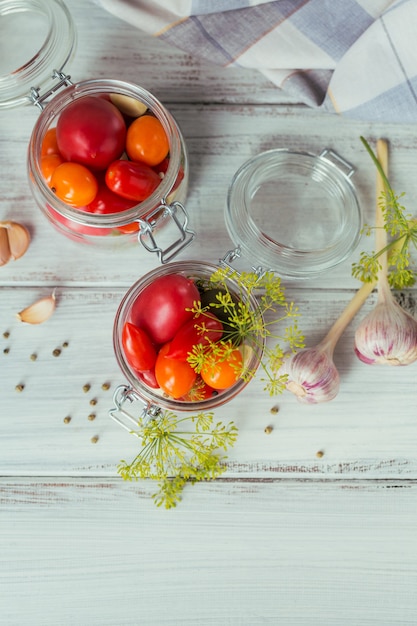 Frische und eingelegte Tomaten, Gewürze und Knoblauch auf einem weißen Holztisch aufbewahren. Gesundes fermentiertes Essen. Gemüsekonserven. Draufsicht