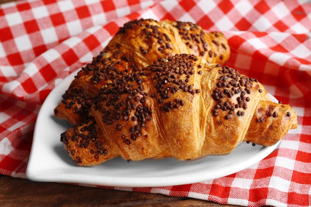 Frische und leckere Croissants mit Schokolade auf Teller auf Holzhintergrund