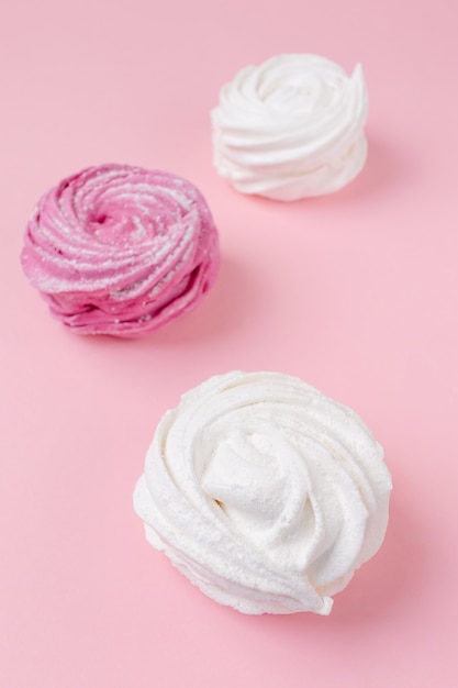 Frische vanille- und beeren-marshmallows auf einem pastellrosa hintergrund.