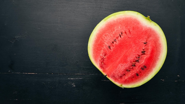 Frische Wassermelone Früchte Melone auf schwarzem Hintergrund aus Holz Freier Platz für Text Ansicht von oben