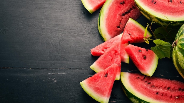 Frische Wassermelone Früchte Melone auf schwarzem Hintergrund aus Holz Freier Platz für Text Ansicht von oben