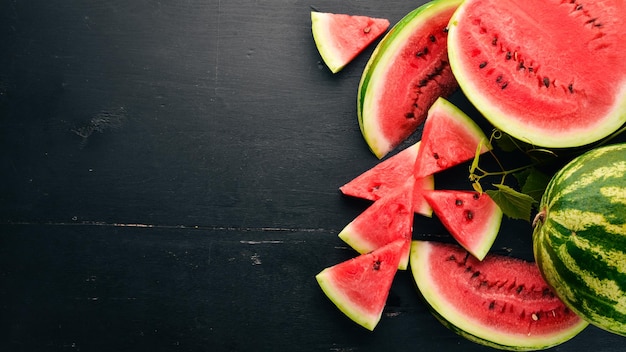 Frische wassermelone früchte melone auf schwarzem hintergrund aus holz freier platz für text ansicht von oben
