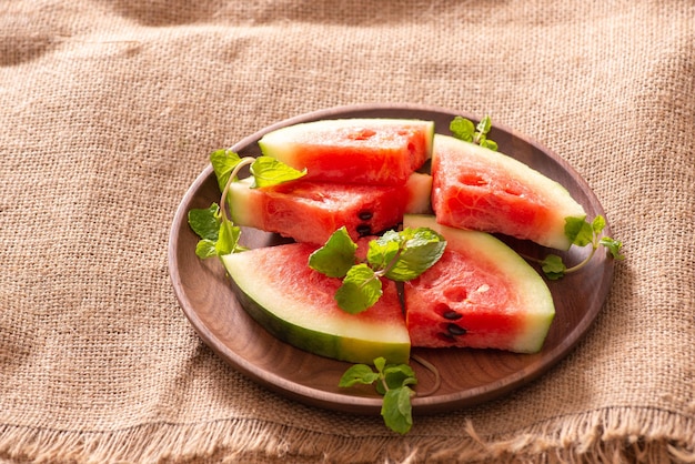 Frische Wassermelone, geschnitten auf einer Holzplatte auf Stoffhintergrund