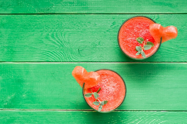 Frische Wassermelone mischte Getränk mit tadellosen Blättern und einem Herzen der Wassermelone in den Gläsern auf einem Holztisch. Ansicht von oben