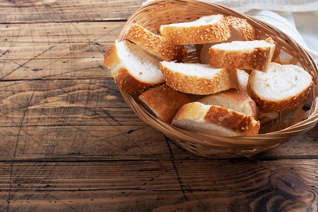 Frische Weißbrot-Baguette-Scheiben in einem Weidenkorb Rustikaler Tischhintergrund aus Holz Kopieren Sie Platz