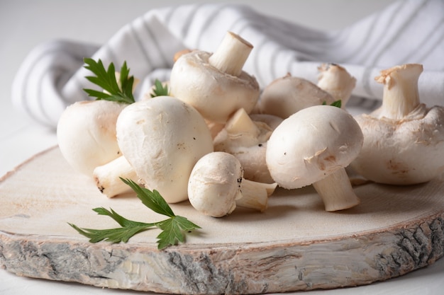 Frische weiße Champignons auf Holzbrett