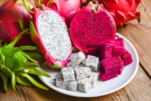 Frische weiße und rote lila Drachenfrucht tropisch im asiatischen Thailand Gesundes Fruchtkonzept Drachenfrucht in Scheiben schneiden und auf weißem Teller mit Pitahaya-Hintergrund halbieren