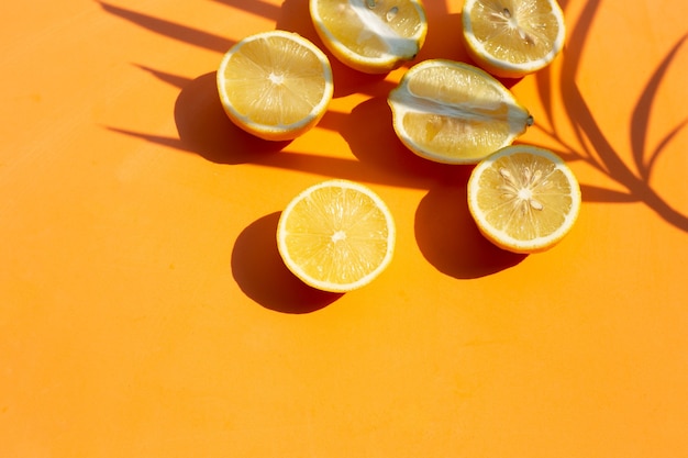 Frische Zitrone mit Palmenblatt auf orange Oberfläche