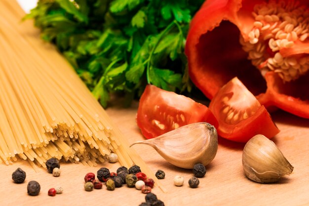 Frische Zutaten zum Kochen: Nudeln und Tomaten, Paprika und Petersilie auf Holztisch Hintergrund.