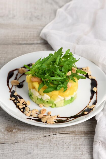 Frischer Avocado-, Mango-, Mozzarella- und Rucola-Salat, gewürzt mit Nüssen