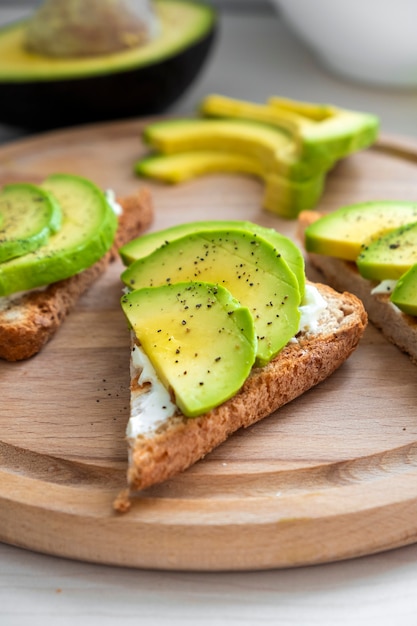 Frischer Avocadotoast mit Weichkäse in Scheiben geschnittenes Avocadosalz und Pfeffer auf Roggenbrot zum Frühstück