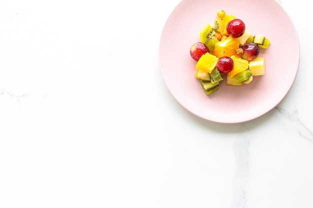 Frischer Bio-Obstsalat auf rosa Teller Gesunde Ernährung und Detox-Diätplan