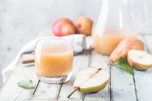 Frischer Birnensaft in Gläsern mit frischen Früchten auf hellem Hintergrund