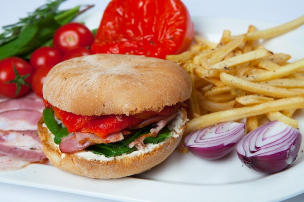 Frischer Burger im Teller mit Gemüse und Pommes frites