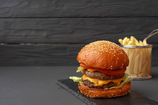 Frischer Burger und Pommes auf schwarzem hölzernem Hintergrund