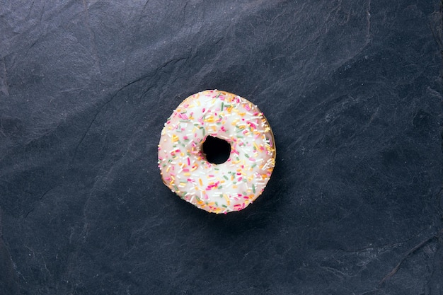 Frischer Donut mit Toppings auf dunklem Hintergrund.