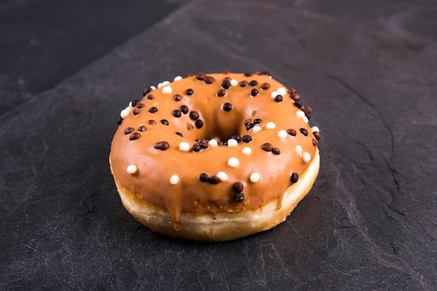 Frischer Donut mit Toppings auf dunklem Hintergrund.