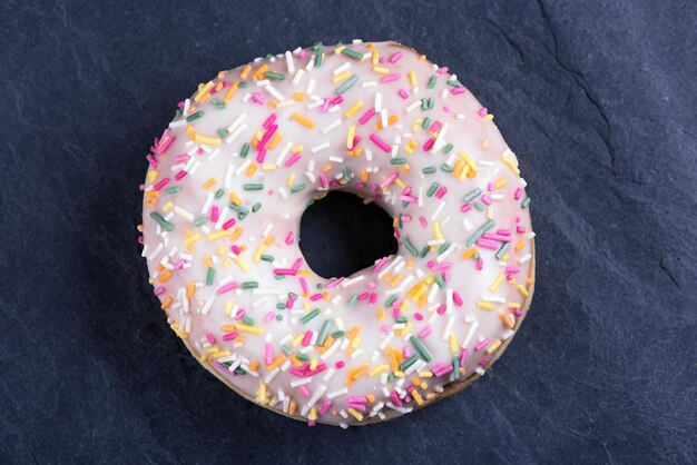 Frischer Donut mit Toppings auf dunklem Hintergrund.