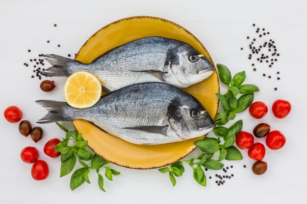 Frischer Dorado-Fisch auf gelbem Teller mit Gemüse. Draufsicht, Kopierraum.