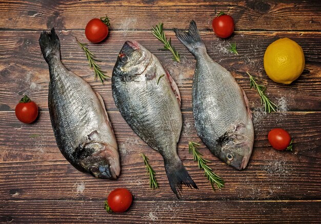 Frischer Dorado Fisch. Dorado und Zutaten zum Kochen auf einem Holztisch.