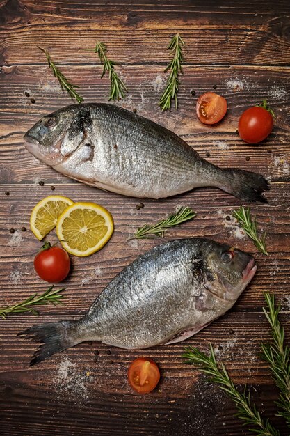 Frischer Dorado Fisch. Dorado und Zutaten zum Kochen auf einem Holztisch.