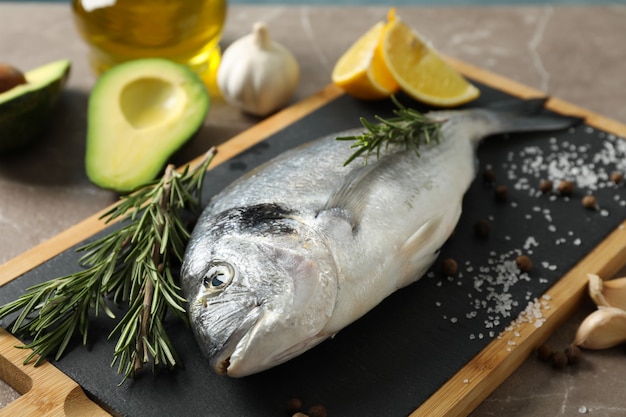 Frischer Dorado-Fisch und kochende Bestandteile auf grauem Hintergrund, Nahaufnahme