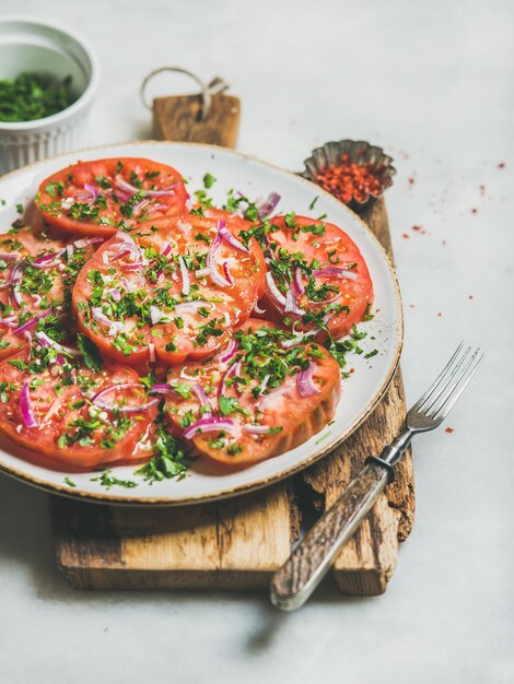 Frischer Erbstück Tomaten Petersilie und Zwiebelsalat auf Holzbrett