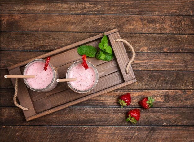 Frischer Erdbeer-Smoothie oder Milchshake und Beeren auf Holztablett Konzept für gesunde Ernährung