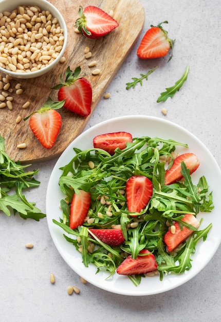 Foto frischer erdbeeren-arugula-salat mit kiefernüssen, der an einem hellen tag serviert wird