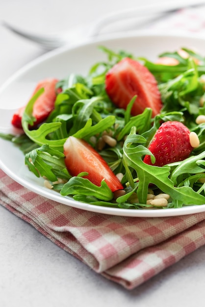 Frischer Erdbeeren-Arugula-Salat mit Kiefernüssen, der an einem hellen Tag serviert wird