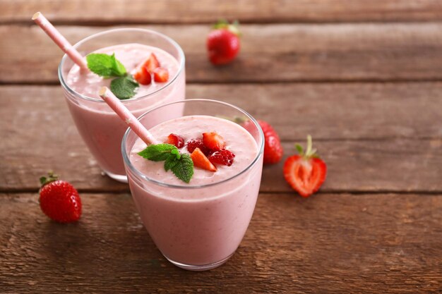 Frischer Erdbeerjoghurt mit Beeren herum auf hölzernem Hintergrund Beschneidungspfad eingeschlossen