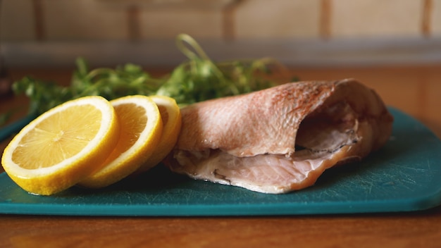 Foto frischer fisch auf einem schneidebrett, rohe kabeljaufilet mit kräuterzusatz und zitrone