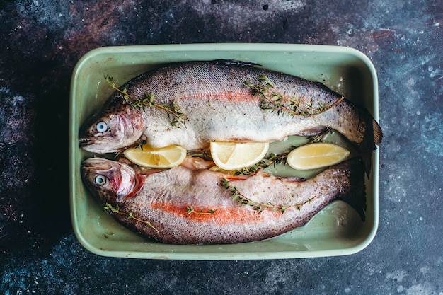 Frischer Fisch vor dem Kochen, gewürzt mit Kräutern, Pfeffer, Thymian und Zitrone.