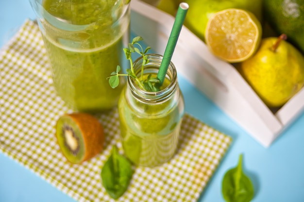 Frischer gemischter grüner Smoothie in Glasflaschen mit Obst und Gemüse