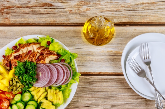 Frischer Gemüsesalat mit gebratener Hühnerbrust, Tomaten, Gurken und Olivenöl in der Flasche