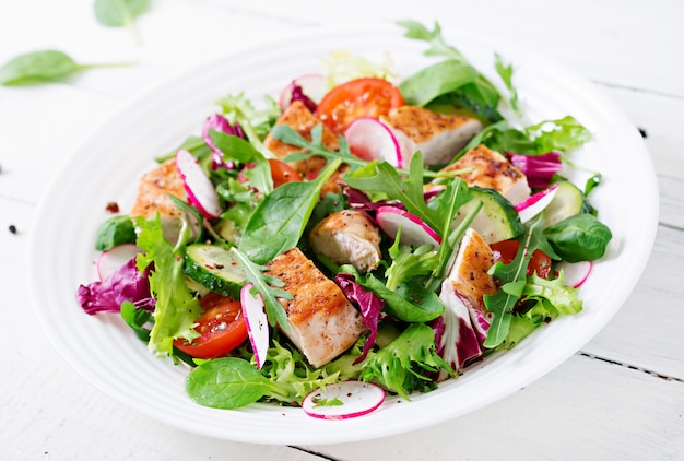 Frischer Gemüsesalat mit gegrillter Hähnchenbrust - Tomaten, Gurken, Radieschen und Salatblättern. Hühnchensalat. Gesundes Essen.