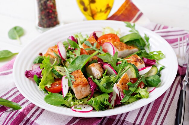 Frischer Gemüsesalat mit gegrillter Hähnchenbrust - Tomaten, Gurken, Radieschen und Salatblättern. Hühnchensalat. Gesundes Essen.