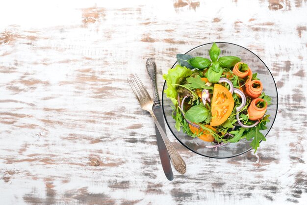 Frischer Gemüsesalat Rucola Tomaten Karotten Zwiebeln Auf einem hölzernen Hintergrund Ansicht von oben Kopieren Sie Platz