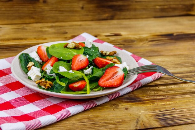 Frischer gesunder Salat mit Erdbeer-Spinat-Walnüssen und Feta-Käse auf Holztisch