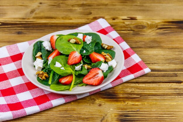 Frischer gesunder Salat mit Erdbeer-Spinat-Walnüssen und Feta-Käse auf Holztisch