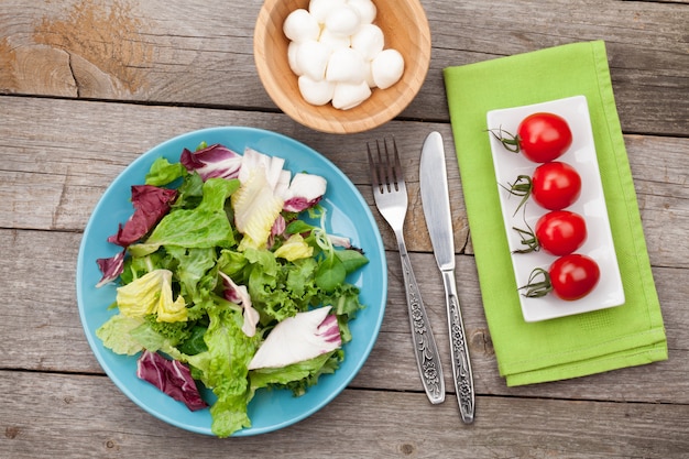 Frischer gesunder Salat, Tomaten, Mozzarella auf Holztisch. Gesundes Essen